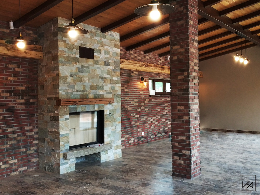 Photo of a large country open concept family room in Other with a home bar, brick floors, a wood stove, a wall-mounted tv and grey floor.