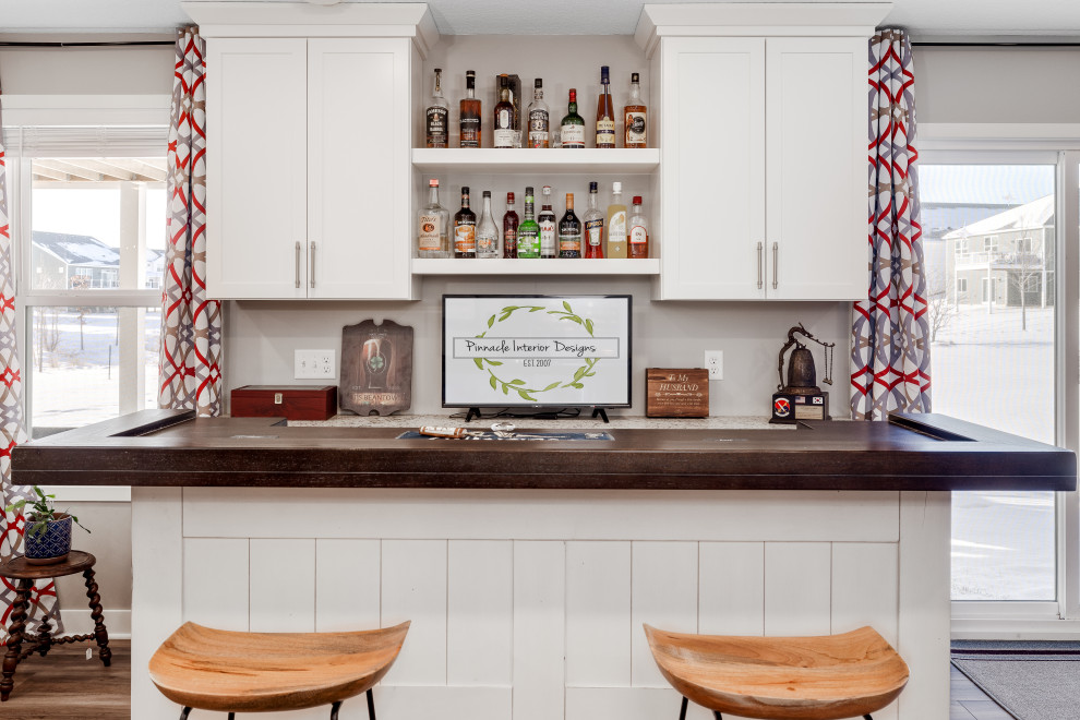 Inspiration for a mid-sized transitional galley home bar in Other with shaker cabinets, white cabinets, wood benchtops, vinyl floors, brown floor and beige benchtop.