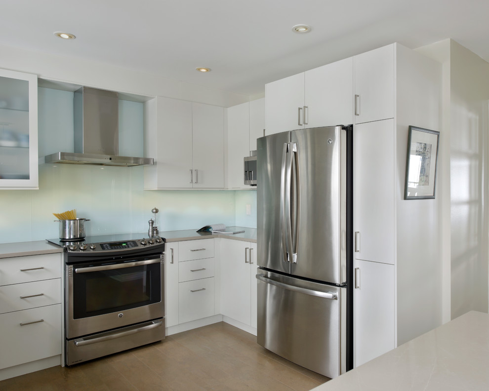 Design ideas for a mid-sized transitional u-shaped separate kitchen in Ottawa with an undermount sink, flat-panel cabinets, white cabinets, quartz benchtops, blue splashback, glass sheet splashback, stainless steel appliances, cork floors and with island.