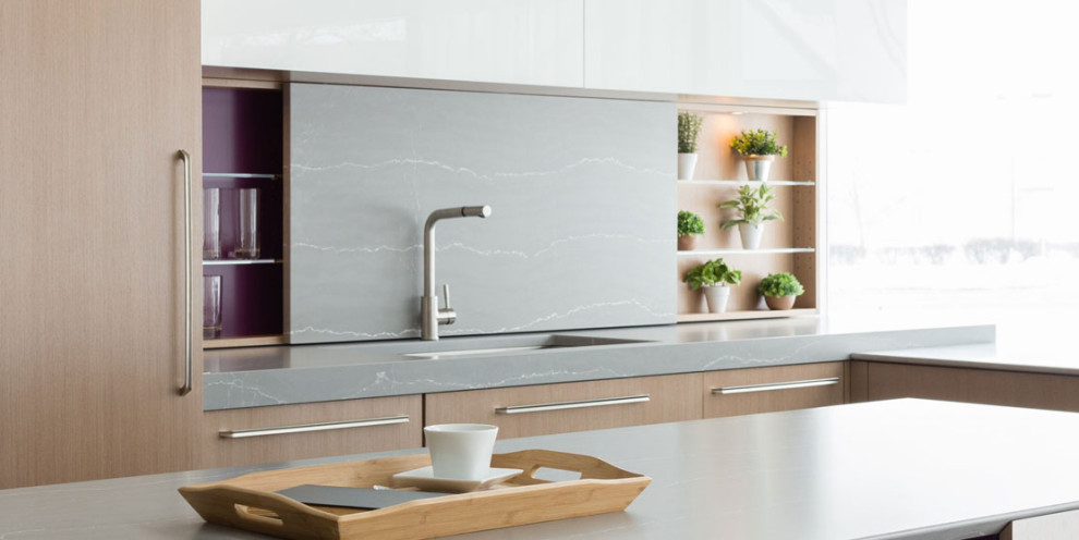 Photo of a small midcentury l-shaped eat-in kitchen in Grand Rapids with flat-panel cabinets, with island, light wood cabinets, quartz benchtops, grey splashback, engineered quartz splashback, stainless steel appliances, concrete floors, grey floor, grey benchtop and an undermount sink.