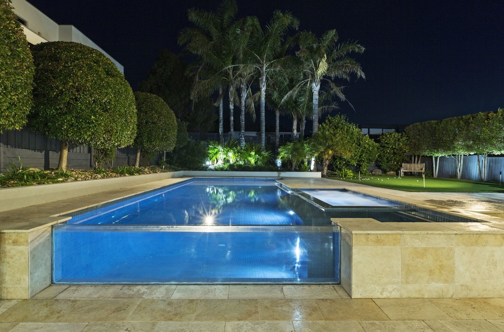 This is an example of a mid-sized traditional backyard rectangular pool in Melbourne with natural stone pavers.