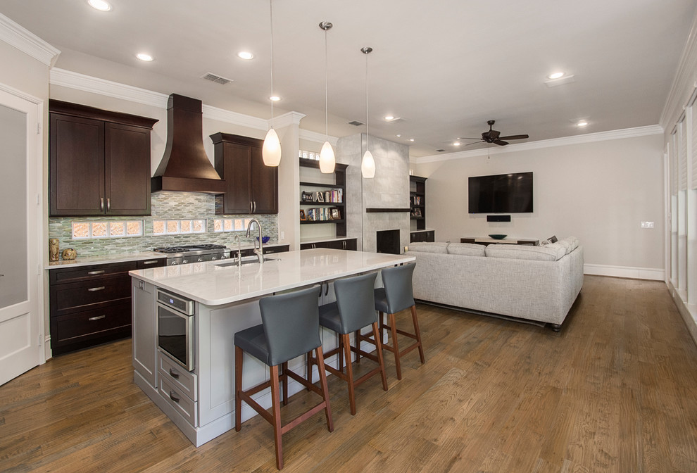 Example of a mid-sized transitional l-shaped medium tone wood floor and brown floor open concept kitchen design in DC Metro with an undermount sink, recessed-panel cabinets, dark wood cabinets, granite countertops, beige backsplash, ceramic backsplash, stainless steel appliances, an island and beige countertops