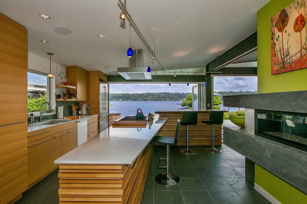 Mid-sized contemporary l-shaped kitchen in Seattle with a single-bowl sink, flat-panel cabinets, light wood cabinets, quartzite benchtops, green splashback, glass tile splashback, stainless steel appliances, slate floors and multiple islands.
