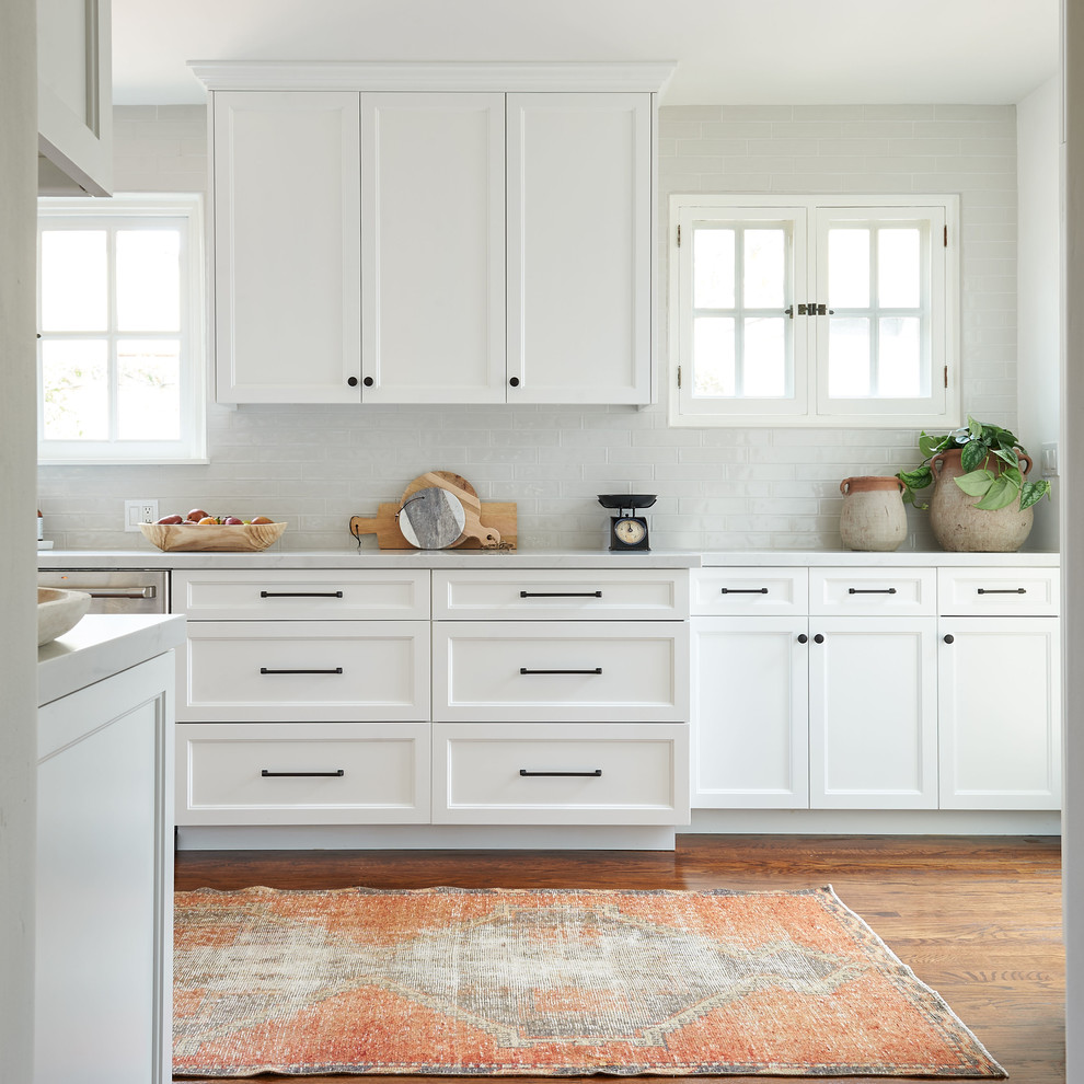 Inspiration for a mid-sized coastal galley medium tone wood floor and brown floor eat-in kitchen remodel in San Diego with an undermount sink, shaker cabinets, white cabinets, quartz countertops, gray backsplash, ceramic backsplash, stainless steel appliances, an island and white countertops