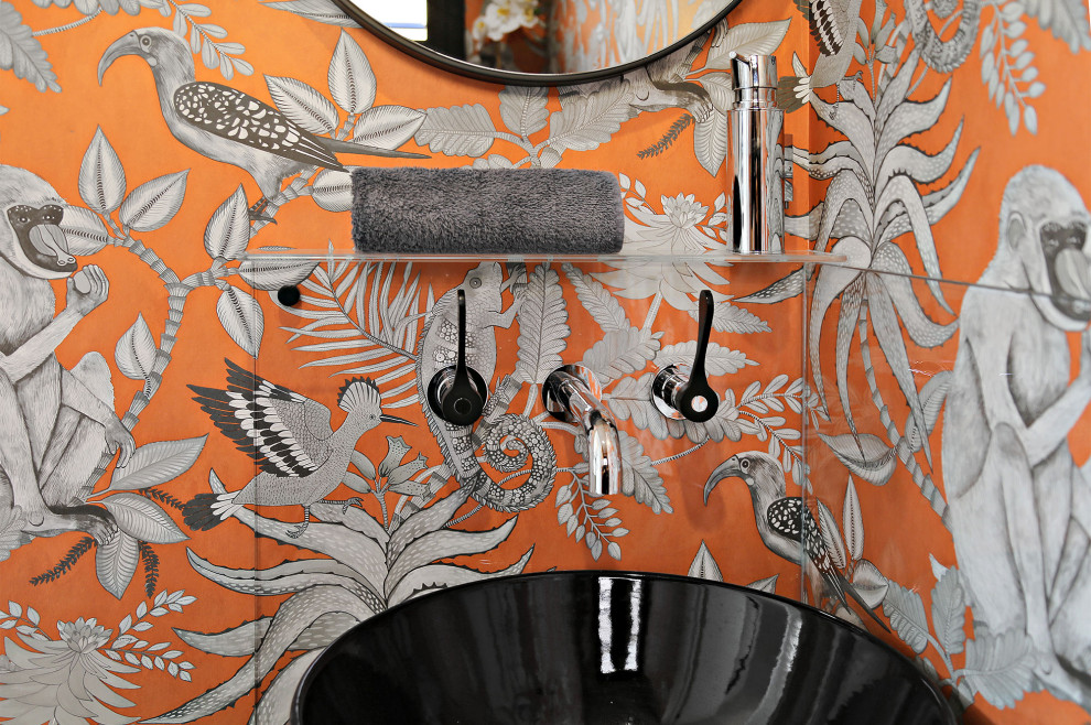 Design ideas for a mid-sized contemporary bathroom in Sydney with a wall-mount toilet, orange walls, a console sink, glass benchtops, a single vanity, a built-in vanity and wallpaper.