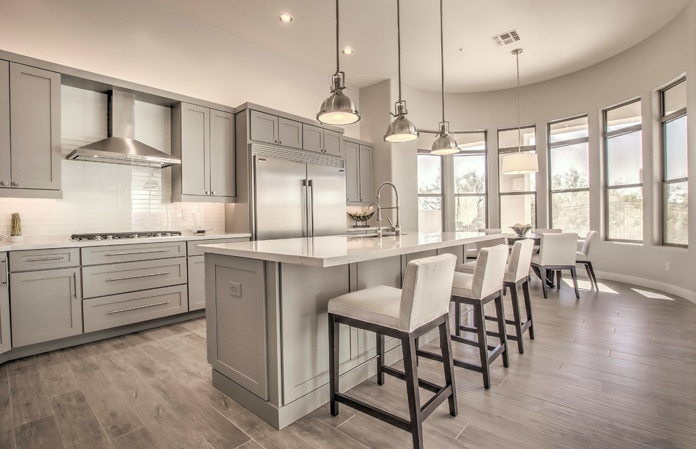 Eat-in kitchen - large transitional l-shaped porcelain tile and brown floor eat-in kitchen idea in Phoenix with an undermount sink, shaker cabinets, beige cabinets, quartz countertops, white backsplash, subway tile backsplash, stainless steel appliances, an island and white countertops