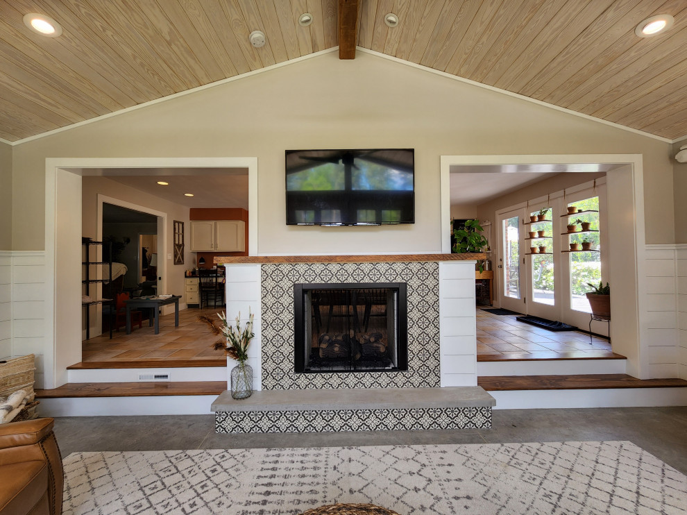 Cette photo montre une véranda nature avec un sol en carrelage de céramique, une cheminée double-face, un manteau de cheminée en carrelage, un plafond standard et un sol gris.