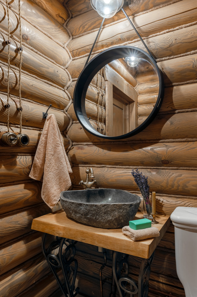 На фото: большой туалет в стиле рустика с коричневыми стенами, настольной раковиной, столешницей из дерева, коричневой столешницей и деревянными стенами