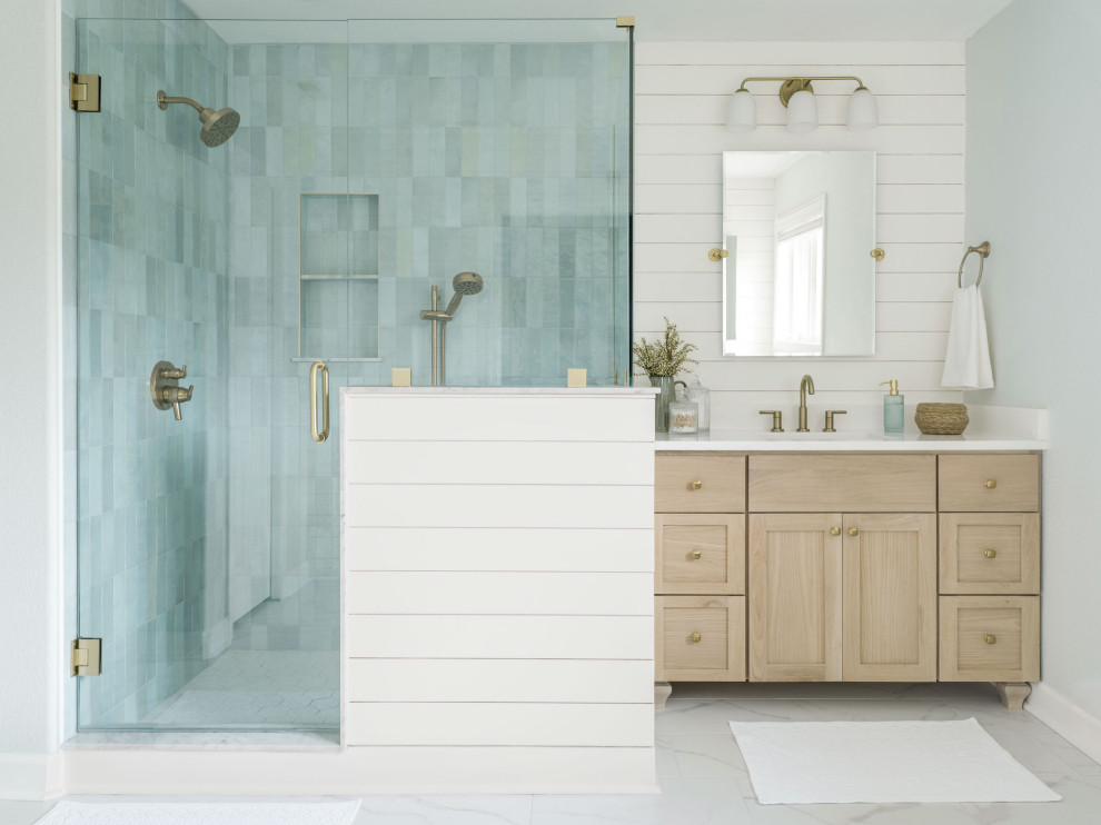 Corner shower - mid-sized coastal master blue tile and ceramic tile ceramic tile, white floor, single-sink and shiplap wall corner shower idea with shaker cabinets, light wood cabinets, blue walls, an undermount sink, quartz countertops, a hinged shower door, white countertops and a built-in vanity