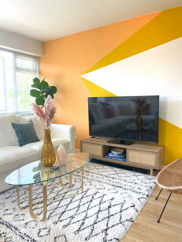 Photo of a mid-sized contemporary open concept living room in West Midlands with multi-coloured walls, laminate floors, a freestanding tv and brown floor.