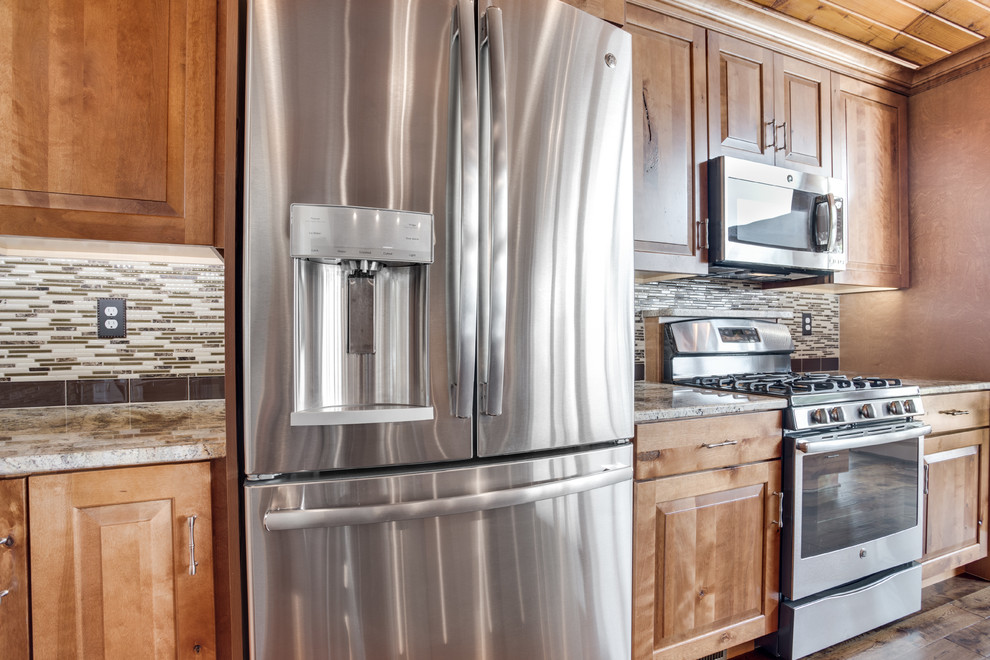 Inspiration for a large rustic kitchen remodel in DC Metro with an undermount sink, raised-panel cabinets, granite countertops, glass tile backsplash, stainless steel appliances and an island