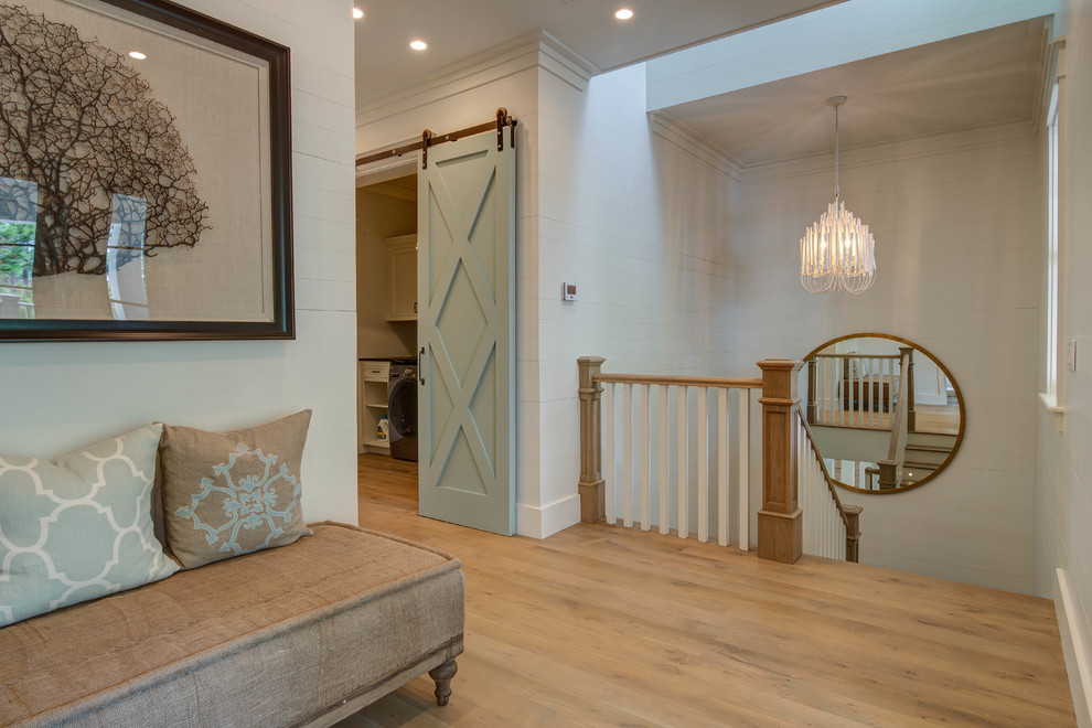 This is an example of an expansive beach style hallway in Atlanta with white walls, light hardwood floors and beige floor.