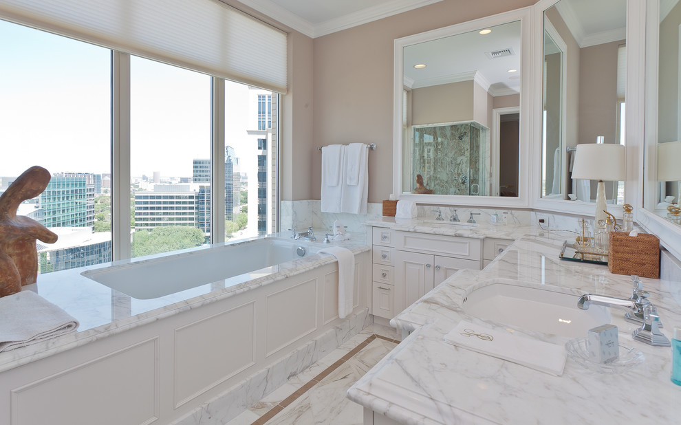 This is an example of a transitional bathroom in Dallas with recessed-panel cabinets, white cabinets, granite benchtops, a drop-in tub, a corner shower and beige walls.