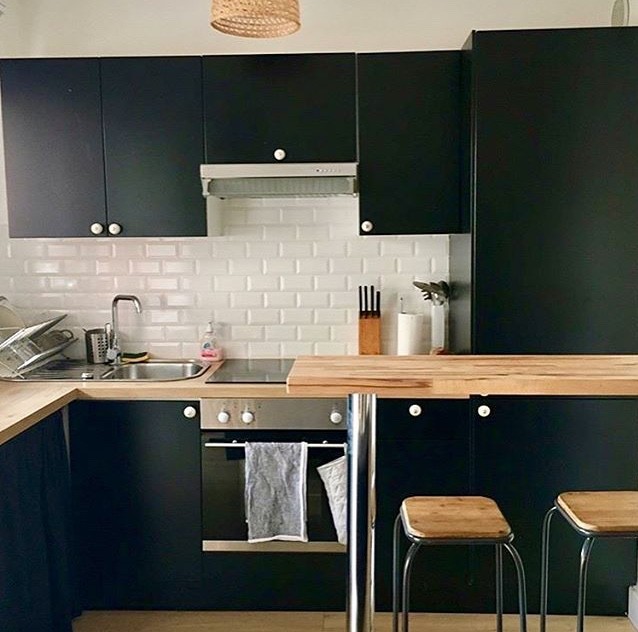 Photo of a small midcentury l-shaped eat-in kitchen in Nice with a single-bowl sink, black cabinets, laminate benchtops, white splashback, subway tile splashback, stainless steel appliances, light hardwood floors, brown floor and brown benchtop.