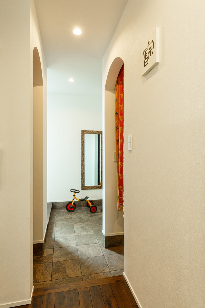 Esempio di un ingresso o corridoio industriale di medie dimensioni con pareti bianche, pavimento marrone e carta da parati