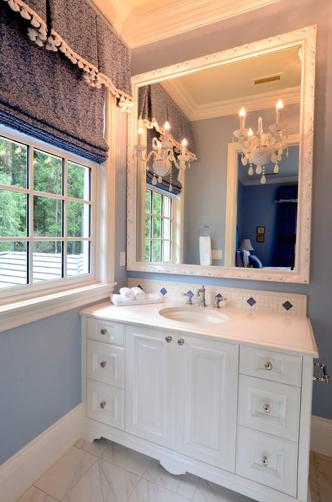 This is an example of a mid-sized contemporary powder room in Seattle with flat-panel cabinets, white cabinets, multi-coloured tile, marble, blue walls, marble floors, an undermount sink, limestone benchtops and white floor.