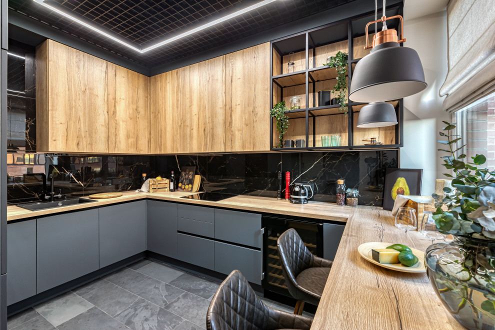 Mid-sized contemporary galley separate kitchen in Moscow with an undermount sink, flat-panel cabinets, black cabinets, wood benchtops, black splashback, porcelain splashback, black appliances, marble floors, with island and brown benchtop.
