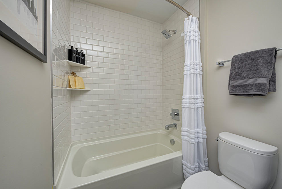 Idées déco pour une salle de bain principale contemporaine de taille moyenne avec un combiné douche/baignoire, WC à poser, une cabine de douche avec un rideau, un carrelage blanc, un carrelage métro, un mur beige et des toilettes cachées.