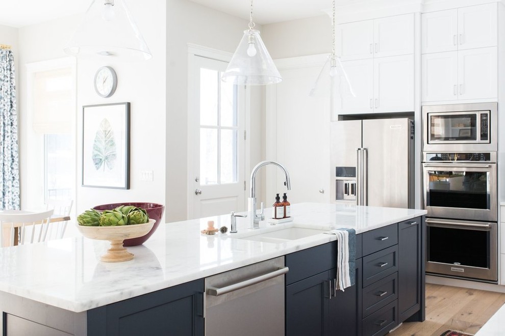 Inspiration for a mid-sized beach style galley eat-in kitchen in Salt Lake City with a drop-in sink, white cabinets, white splashback, subway tile splashback, light hardwood floors and with island.