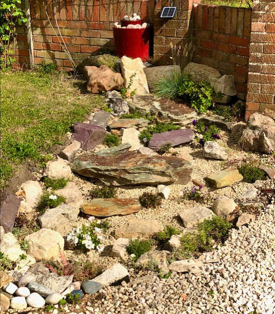 Small modern front driveway full sun garden wall for summer in Oxfordshire with a rockery and decorative stones.