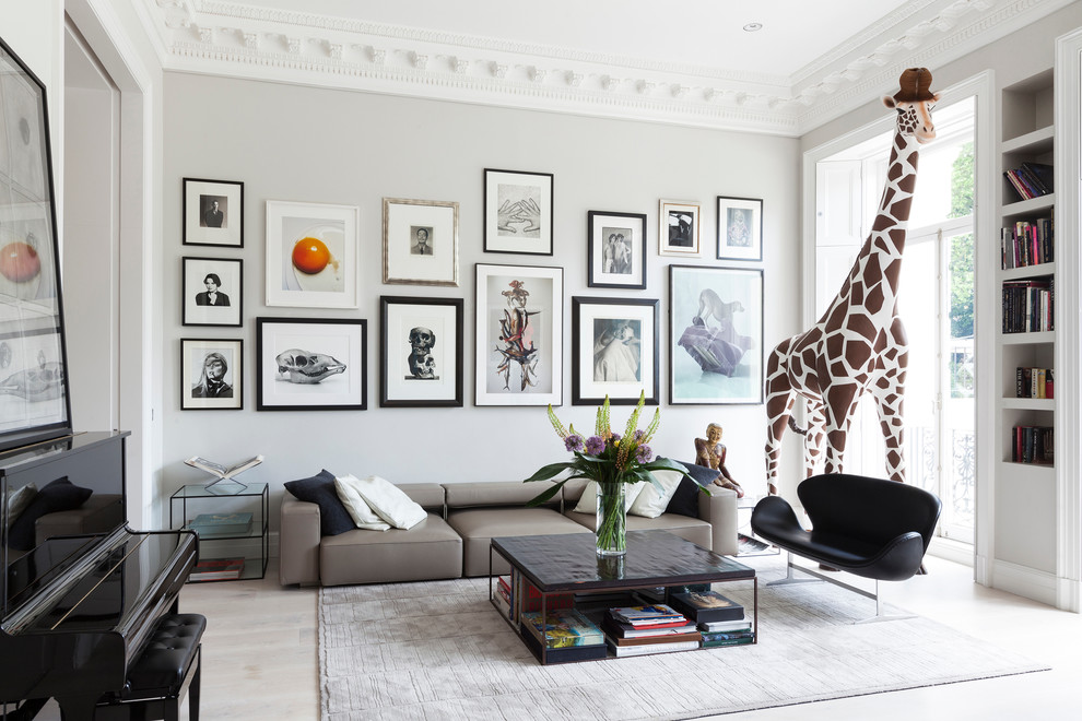 Eclectic enclosed family room in London with a music area, grey walls and light hardwood floors.