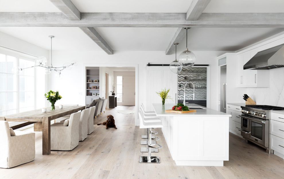 Transitional galley light wood floor and beige floor open concept kitchen photo in New York with an undermount sink, shaker cabinets, white cabinets, stainless steel appliances and an island