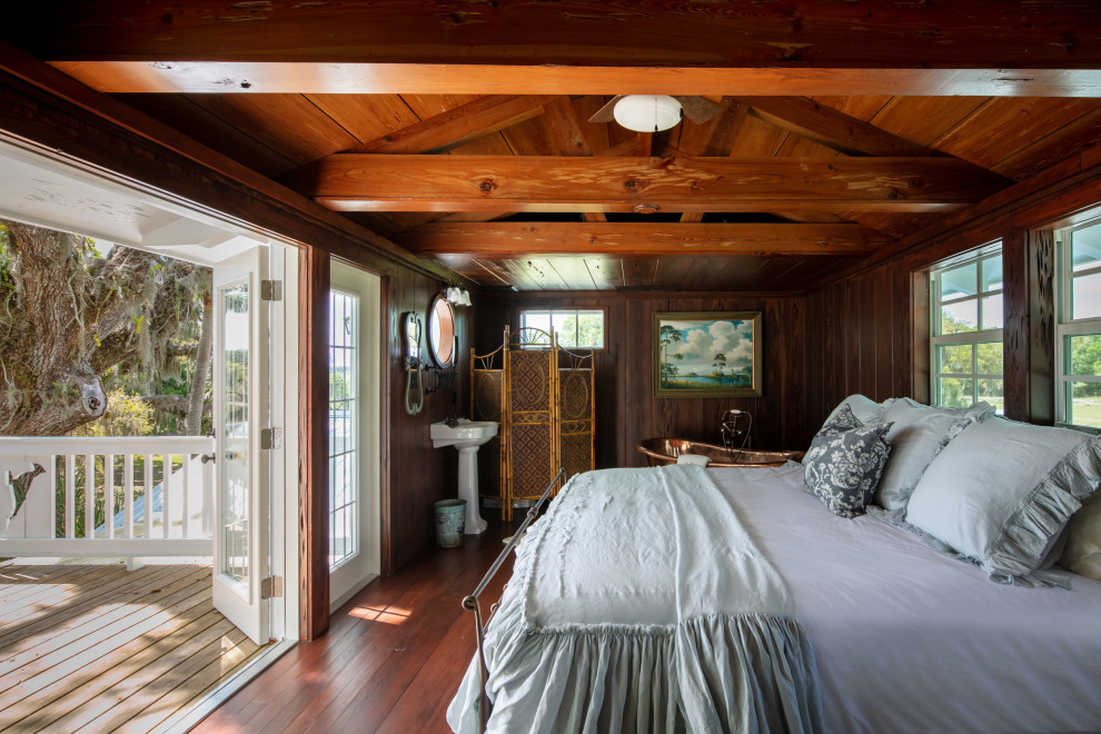 Diseño de dormitorio principal de estilo de casa de campo grande sin chimenea con suelo de madera oscura, vigas vistas y madera