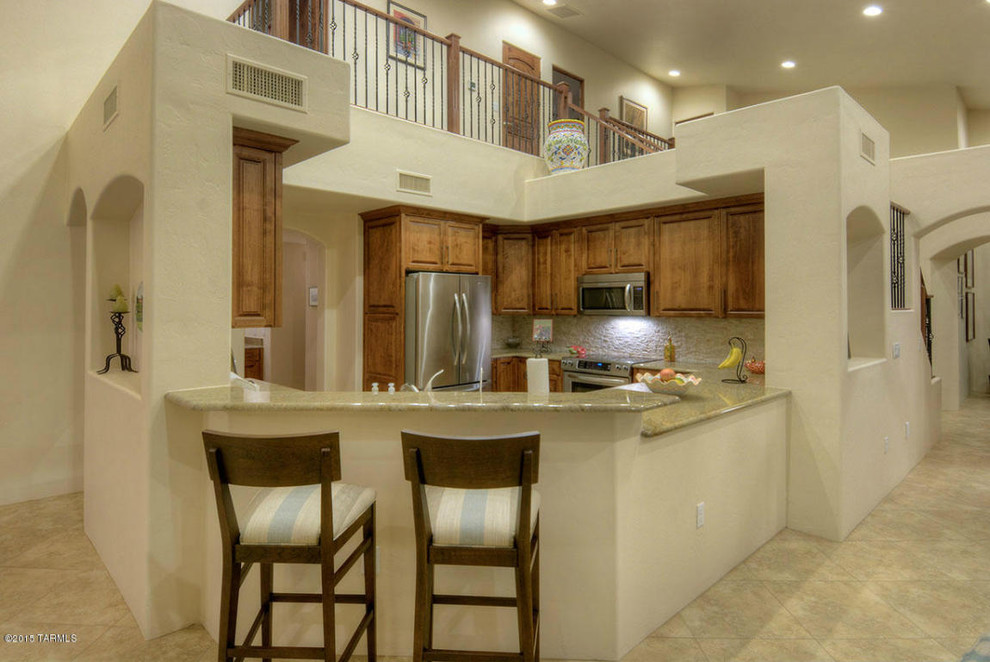 Inspiration for a mid-sized timeless l-shaped ceramic tile eat-in kitchen remodel in Phoenix with a drop-in sink, raised-panel cabinets, brown cabinets, granite countertops and stainless steel appliances