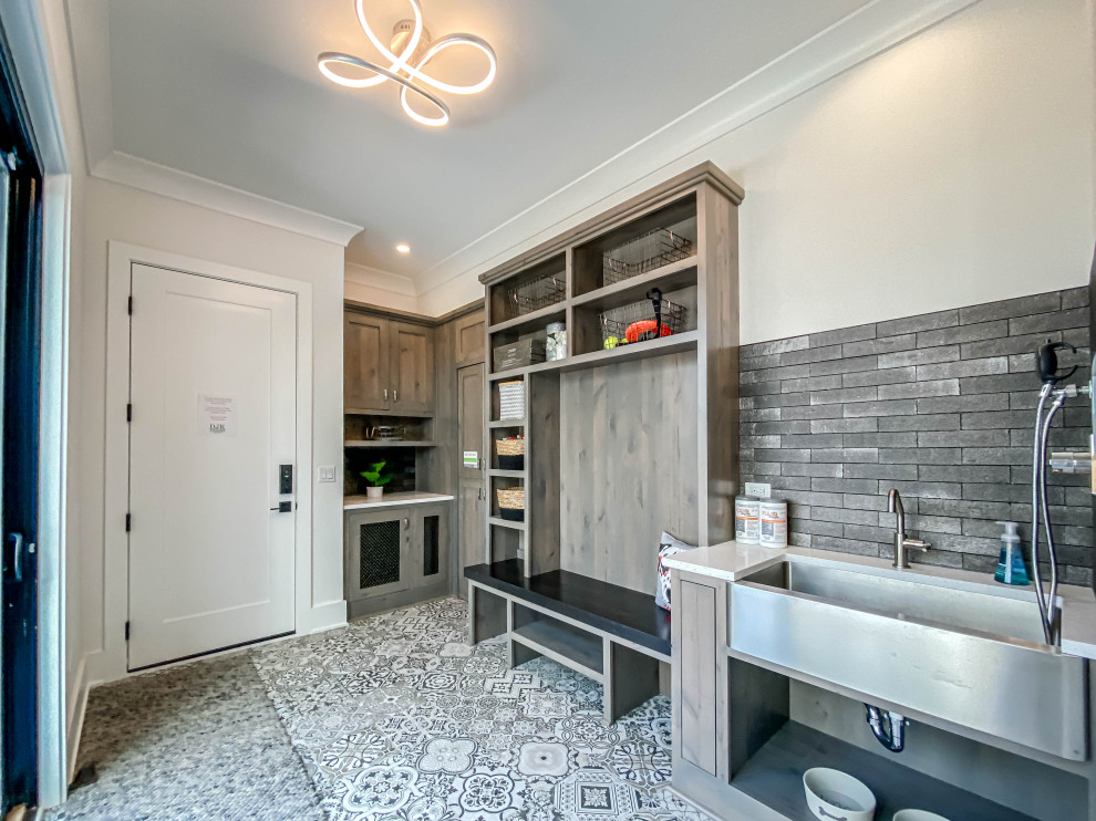 Large industrial galley utility room in Chicago with a farmhouse sink, shaker cabinets, distressed cabinets, quartz benchtops, grey splashback, brick splashback, white walls, ceramic floors, white floor, white benchtop and brick walls.