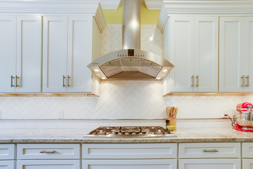 Inspiration for a mid-sized transitional u-shaped medium tone wood floor and brown floor eat-in kitchen remodel in Birmingham with a farmhouse sink, shaker cabinets, white cabinets, granite countertops, white backsplash, subway tile backsplash and stainless steel appliances
