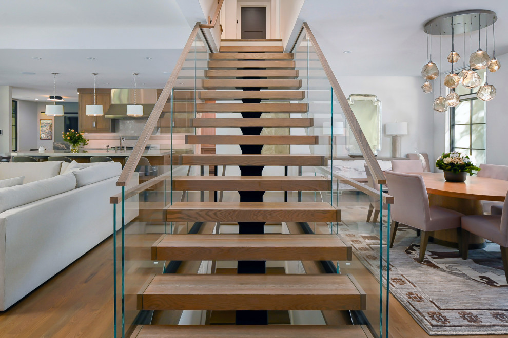 На фото: лестница на больцах в стиле неоклассика (современная классика) с деревянными ступенями, стеклянными подступенками и деревянными перилами