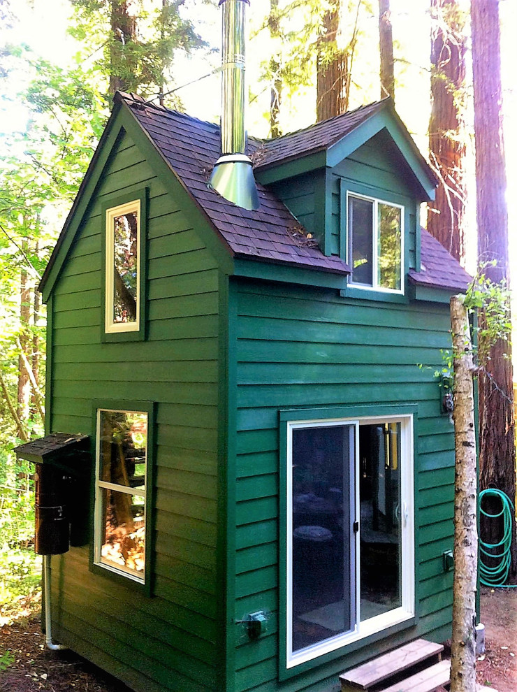 Idée de décoration pour une petite façade de Tiny House verte chalet en panneau de béton fibré à un étage avec un toit à deux pans, un toit en shingle et un toit marron.