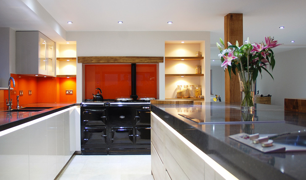 This is an example of a contemporary kitchen in Sussex with quartz benchtops, orange splashback and glass sheet splashback.
