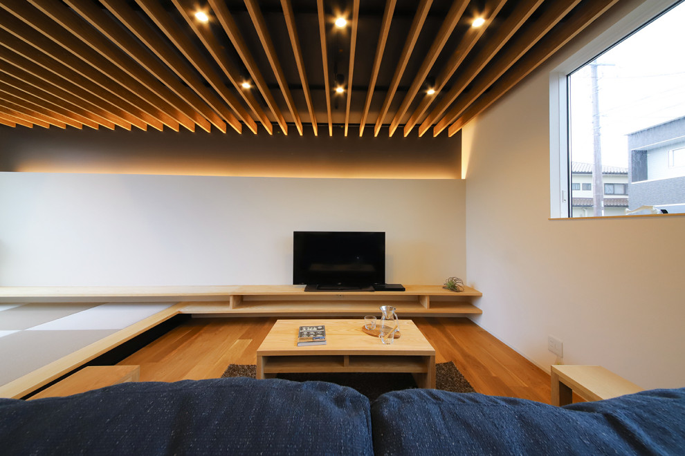 Идея дизайна: открытая гостиная комната в стиле модернизм с белыми стенами, полом из фанеры, отдельно стоящим телевизором, коричневым полом и многоуровневым потолком без камина