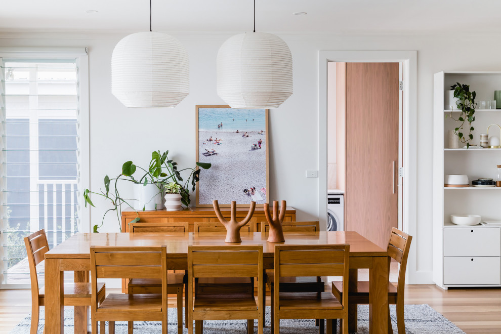 Cette image montre une salle à manger ouverte sur le salon design de taille moyenne avec un sol en bois brun, un mur blanc et un sol marron.