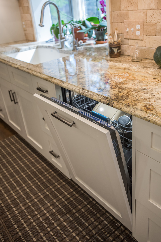 Example of a large transitional u-shaped medium tone wood floor and brown floor eat-in kitchen design with an undermount sink, shaker cabinets, white cabinets, granite countertops, beige backsplash, paneled appliances and an island