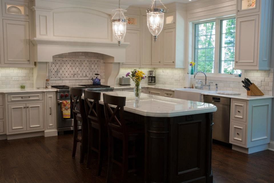 Design ideas for a large traditional u-shaped kitchen in Chicago with a farmhouse sink, white cabinets, quartzite benchtops, subway tile splashback, stainless steel appliances, medium hardwood floors, with island, brown floor, recessed-panel cabinets and grey splashback.