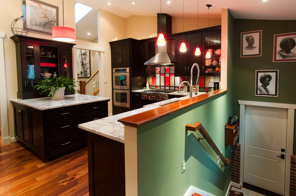 Transitional u-shaped open concept kitchen photo in DC Metro with an undermount sink, shaker cabinets, dark wood cabinets, granite countertops, red backsplash, glass tile backsplash and stainless steel appliances