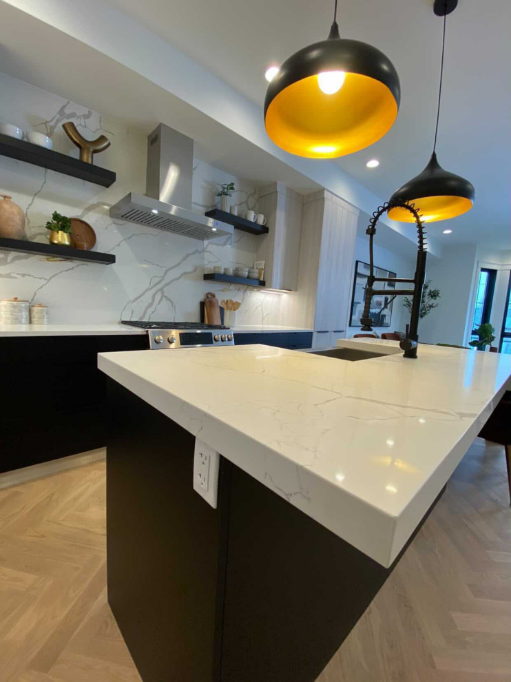This is an example of a large modern l-shaped kitchen/diner in Boston with a belfast sink, engineered stone countertops, white splashback, engineered quartz splashback, stainless steel appliances, light hardwood flooring, multiple islands, brown floors and white worktops.