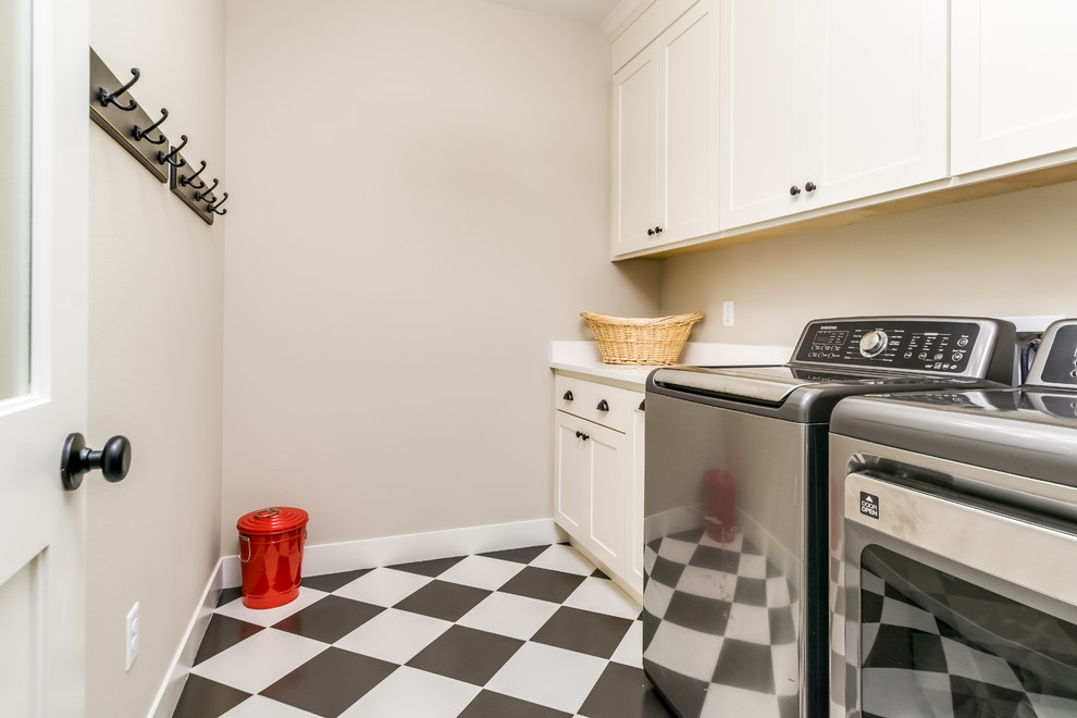 Photo of a mid-sized country single-wall dedicated laundry room in Denver with an undermount sink, shaker cabinets, white cabinets, solid surface benchtops, beige walls, porcelain floors, a side-by-side washer and dryer, multi-coloured floor and white benchtop.