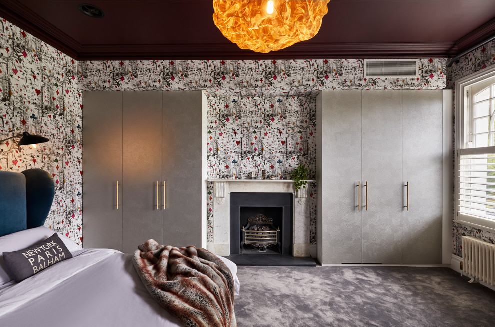 Cette photo montre une chambre tendance avec un mur multicolore, un manteau de cheminée en pierre, un sol gris et du papier peint.