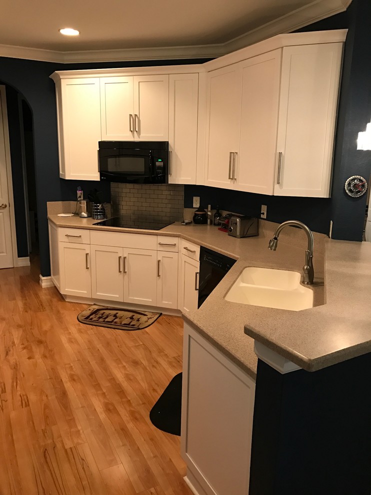 Eat-in kitchen - small transitional galley bamboo floor eat-in kitchen idea in Miami with an undermount sink, shaker cabinets, white cabinets, solid surface countertops and stainless steel appliances