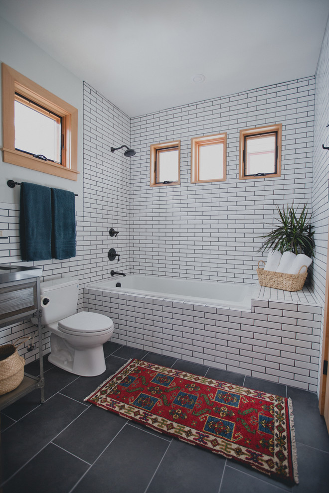 Small transitional bathroom in Portland with brown cabinets, a drop-in tub, a one-piece toilet, white tile, porcelain tile, white walls, porcelain floors, a console sink, engineered quartz benchtops, a shower/bathtub combo, grey floor, an open shower and raised-panel cabinets.