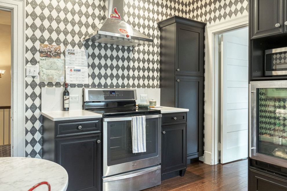 Esempio di una cucina lineare classica chiusa con ante in stile shaker, ante nere, top in quarzo composito, elettrodomestici in acciaio inossidabile, pavimento in legno massello medio, top bianco e paraspruzzi bianco