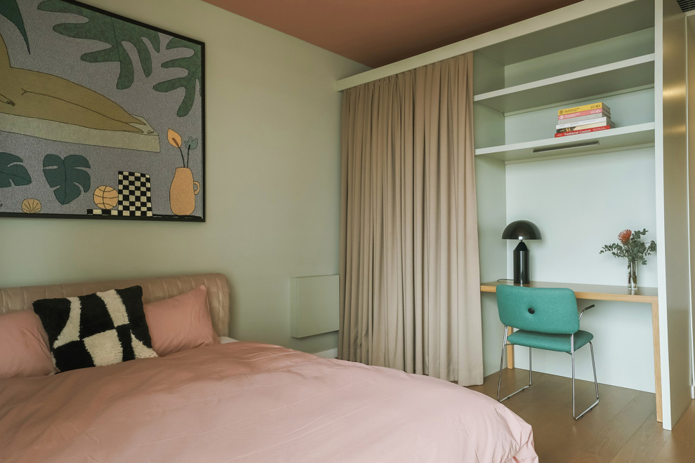 Modelo de dormitorio principal actual de tamaño medio con paredes verdes, suelo de madera clara y suelo marrón
