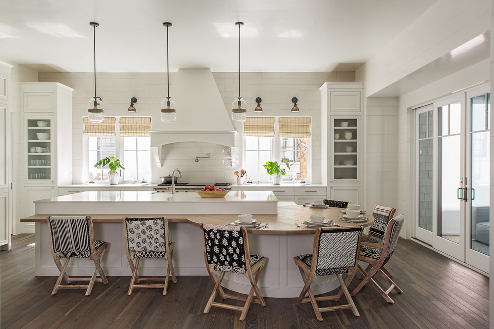 Beach style l-shaped eat-in kitchen in Charleston with recessed-panel cabinets, white cabinets, white splashback, stainless steel appliances, dark hardwood floors, with island, brown floor and white benchtop.