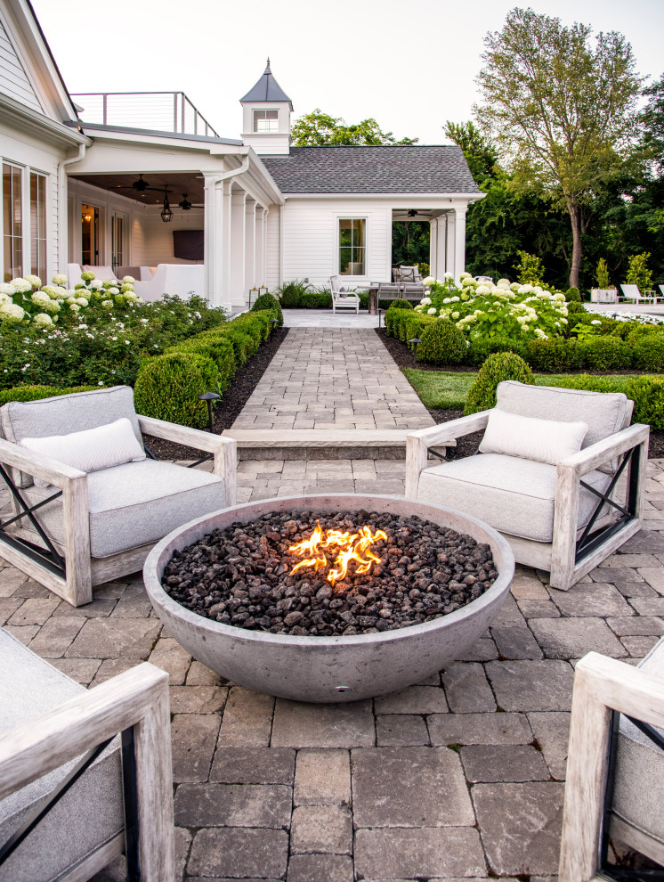 This is an example of a mid-sized country side yard patio in Nashville with a fire feature, natural stone pavers and no cover.