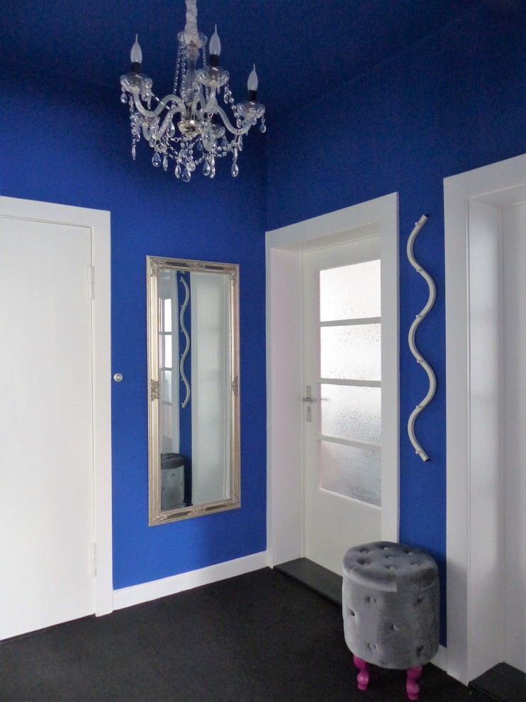 Kleiner Stilmix Flur mit blauer Wandfarbe, Teppichboden und schwarzem Boden in Berlin