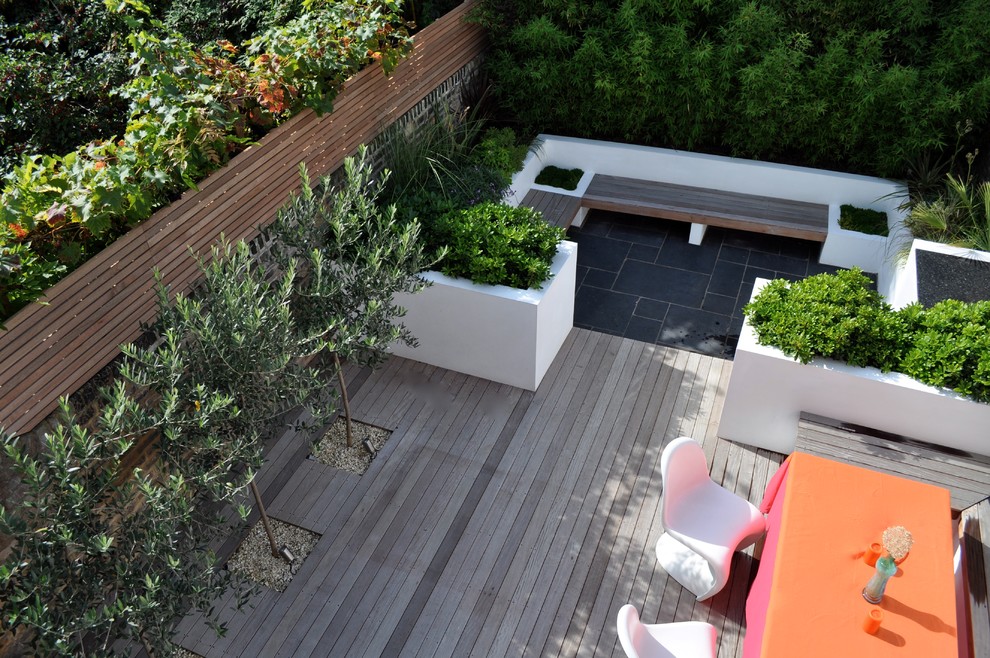 Design ideas for a mid-sized contemporary backyard full sun formal garden in London with decking.