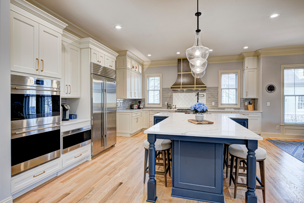 Example of a mid-sized transitional l-shaped medium tone wood floor and beige floor enclosed kitchen design in Indianapolis with an undermount sink, shaker cabinets, white cabinets, granite countertops, gray backsplash, subway tile backsplash, stainless steel appliances, an island and white countertops
